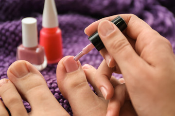 Woman doing pedicure on color background, closeup