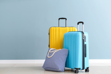 Packed suitcases and beach bag near color wall - obrazy, fototapety, plakaty