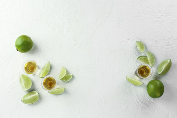 Composition with shots of tequila and lime on white background