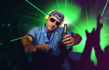 young happy and cool DJ playing music at party event in night club mixing techno songs on laser and...