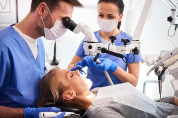 Mannelijke tandarts die met tandmicroscoop werkt