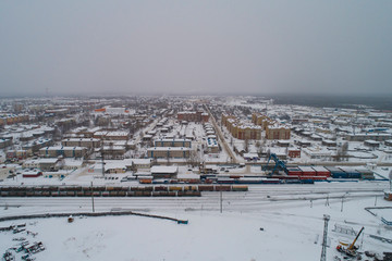 Sovetskiy city. Railway station Verkhnekondinskaya and the trains.  Aerial. Winter, snow, cloudy. Khanty Mansiysk Autonomous Okrug (HMAO), Russia.