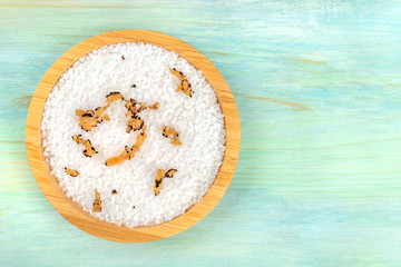 A bowl of sea salt infused with truffle shavings, shot from above on a teal blue background with a place for text