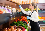 Salesgirl arranging goods in greengrocery