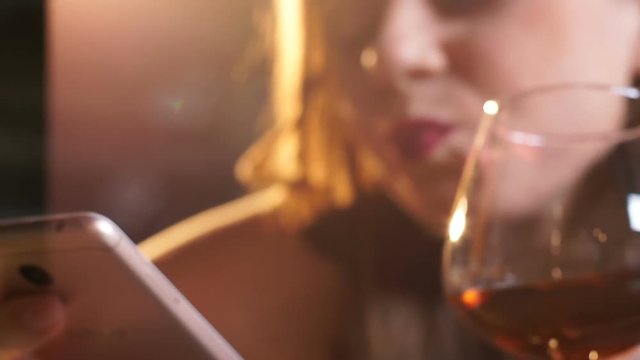 Depressed drunk woman drinking brandy and texting message to ex-boyfriend