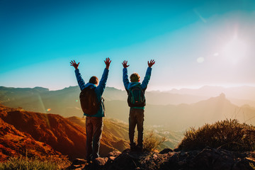 Happy father and son hiking at sunset mountains