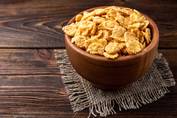 Corn flakes on dark wooden background.