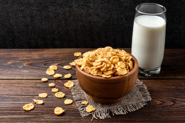 Corn flakes on dark wooden background.