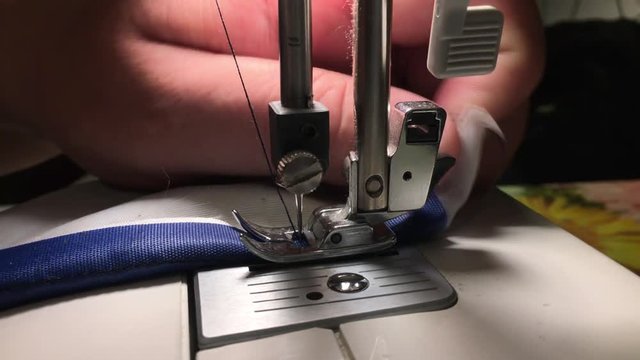 Worker stitches cloth on the sewing machine. Cratches the thread on the fabric.