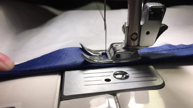 Worker stitches cloth on the sewing machine. Cratches the thread on the fabric.