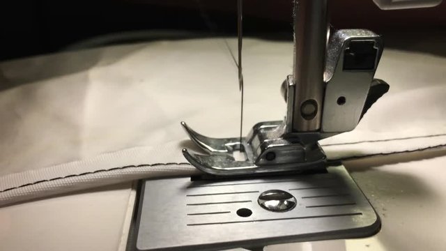 Worker stitches cloth on the sewing machine. Cratches the thread on the fabric.