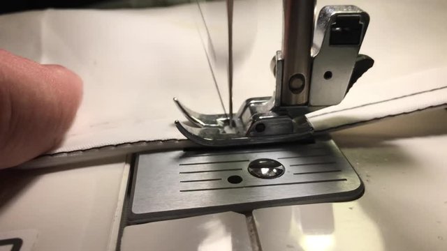 Worker stitches cloth on the sewing machine. Cratches the thread on the fabric.