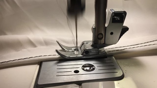 Worker stitches cloth on the sewing machine. Cratches the thread on the fabric.