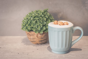 Caramel Popcorn Latte (no caffeine) in light blue mug and potted plant