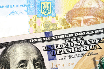 A blue and yellow one hryvnia bank note from Ukraine with a blue one hundred American dollar bill close up in macro