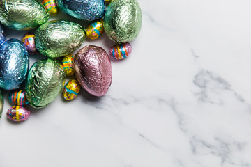 Easter egg chocolate treats wrapped in shiny coloured foil on  marble background
