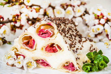 Dessert cake cherry slide and flowering branches of apricot. On wooden background