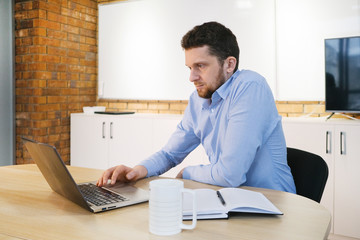 Business man working on a project sitting at office desk using laptop computer.