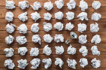 Ideological concept with wastepaper light bulb on wooden table