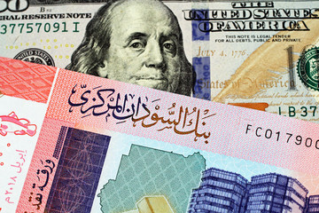 A close up image of an American one hundred dollar bill with a colorful fifty pound note from Sudan in macro