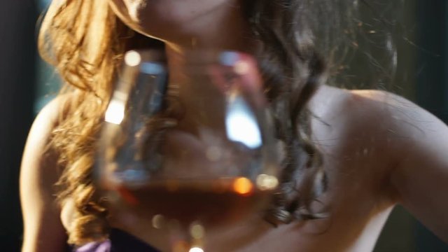 Seductive woman playing with hair and flirting, glass of brandy on bar counter