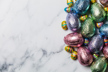Easter egg chocolate treats wrapped in shiny coloured foil on  marble background