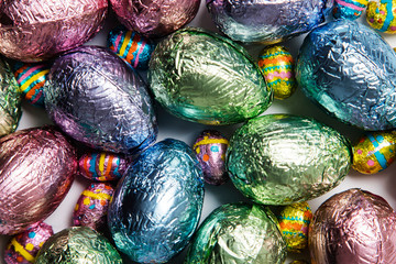 Easter egg chocolate treats wrapped in shiny coloured foil on  marble background