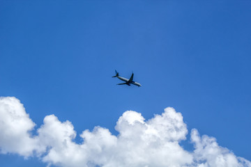 The plane flies in the sky with clouds.
