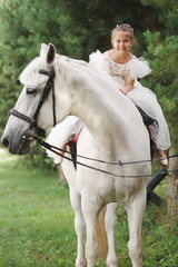 happy little princess on white horse in the forest