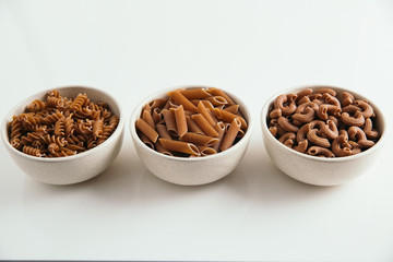 Variety of whole grain pasta, white background