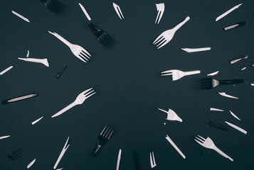 Plastic pollution concept. No to plastic. Broken single-use white and black forks on dark background. New rules to reduce plastic waste, EU directive. We can no longer pollute our planet. Top view