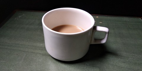 A white cup half filled with tea.