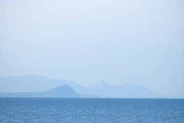 Blurred deep blue sea with water waves and mountains view for background backdrop 