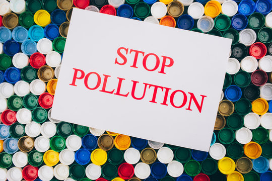 Plastic pollution concept. Refuse single-use plastic. Paper with words Stop Pollution on colored background of different plastic lids, top view. Single-use plastics, EU European directive to help