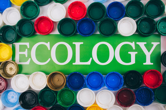 Recycling, reuse, reduce concept. Word Ecology in the center of colored background of different plastic lids, top view. Recycling bottle lids. Single-use plastics, EU European directive. Save ecology