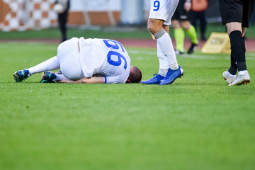 The injured footballer lies on the pitch.