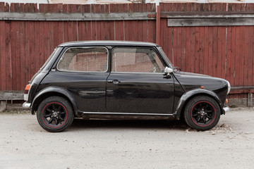Black old classic mini cuper. Street and wooden yard. Travel photo 2019.