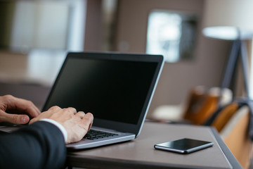 Manager on his laptop and phone. Boss at the desk, typing on laptop, using phone. 