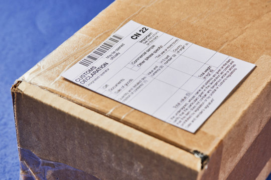 Parcel with Customs declaration form CN22 on a blue velvet background. Close-up