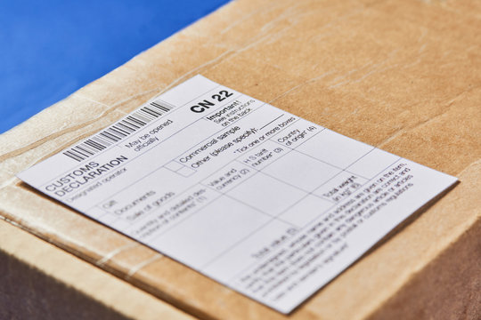 Parcel with Customs declaration form CN22 on a blue velvet background. Close-up