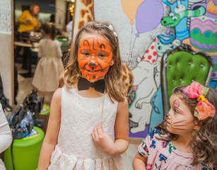 Portrait of two little girls with face painting at birthday party