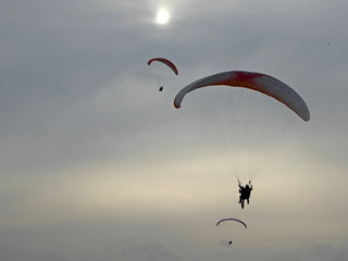 Paragliders in silhoette on a cloudy day