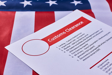 Fototapeta na wymiar Page with the rules of customs clearance on American flag background. Close-up