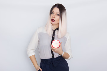 Blonde woman holding red alarm clock in her hands