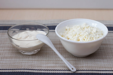 Cottage cheese and sour cream in bowls on the table. View from above.