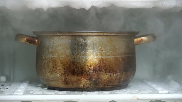 Defrosting a refrigerator using big kitchen saucepan full of hot water