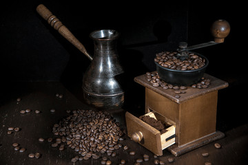 The photo was taken in the technique of "Light brush". On the table are a coffee grinder and a Turk, scattered around the coffee beans.