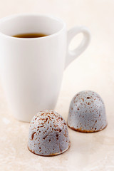 Luxury handcrafted bonbons with cup of coffee espresso on beige marble background
