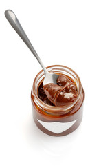 Spoon of homemade chocolate caramel sauce on jar isolated on white