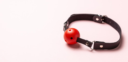 Red Ball gag on pink background. Intimate toys. Sex abuse slavery